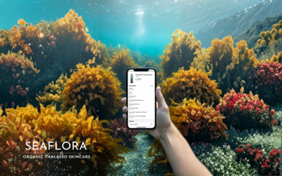 Hand holding phone showing Yuka app 100/100 excellent score for clean beauty against background of Pacific Ocean and wild seaweed.