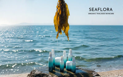 Multiple Seaflora skincare bottles beside pristine kelp seaweed being gently lifted from clear ocean water, representing natural marine ingredients.