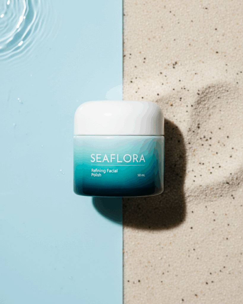 Seaflora Refining Facial Polish jar next to a small pile of fine natural exfoliating grains on a surface transitioning to smooth, clear water.