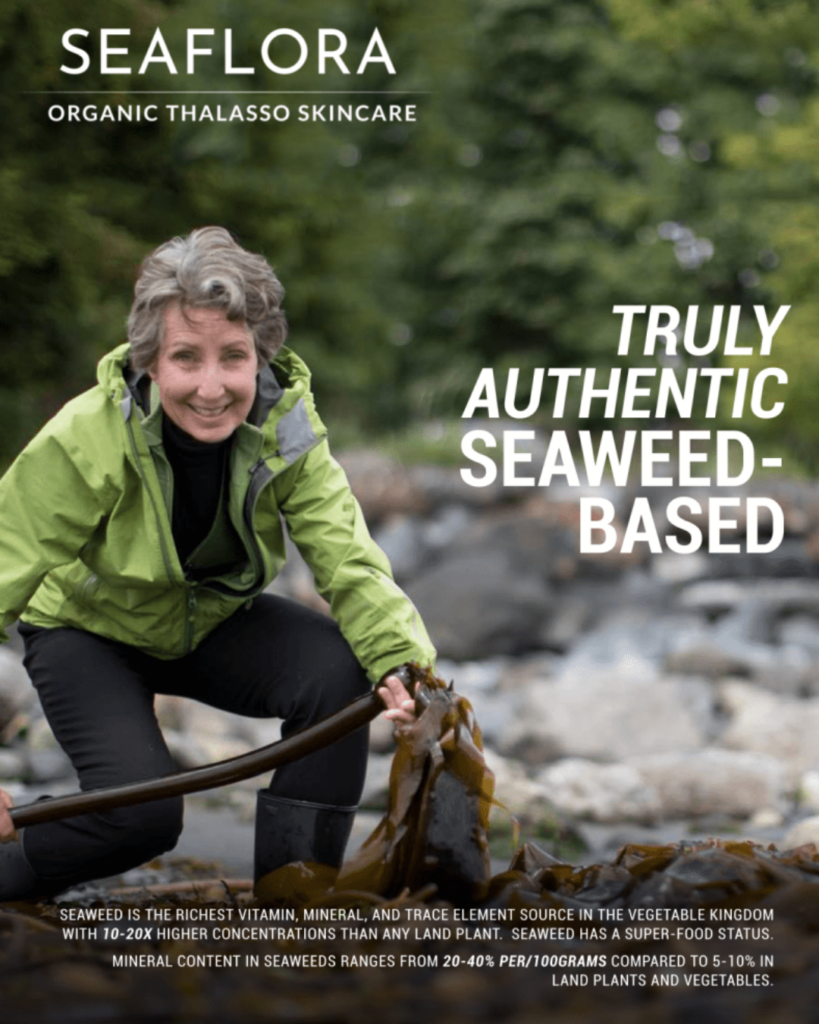 Diane (founder) smiling while holding a large strand of kelp on a rocky beach, with text about Seaflora Organic Thalasso Skincare.