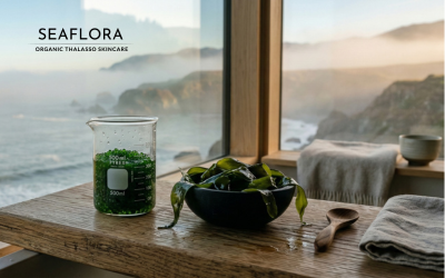 A cinematic, wide-angle photograph of a minimalist wooden spa counter overlooking a misty coastal cliffside at dawn. On the counter sits a glass lab beaker filled with emerald-green seaweed pearls and a dark obsidian bowl holding fresh, glistening sugar kelp fronds.